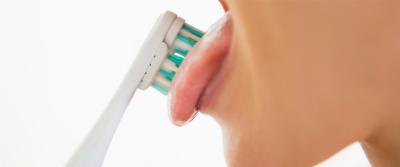 A girl brushes her tongue as a good oral hygiene practice