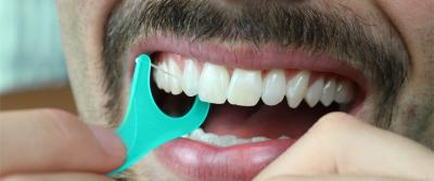 A boy flosses his white teeth to maintain his oral hygiene