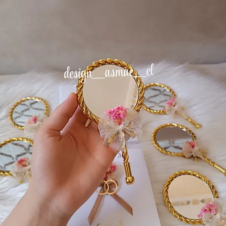 مرآة يد ذهبية مزينة كتو توزيعة حناء أنيقة مع شريط فيونكة وزينة زهرية.