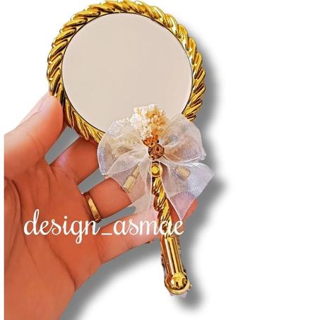 مرآة يد ذهبية مزينة كتو توزيعة حناء أنيقة مع شريط فيونكة وزينة زهرية.