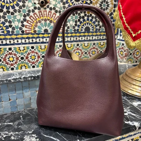 حقيبة يد جلدية بتفاصيل دقيقة وشعار ذهبي رقيق.