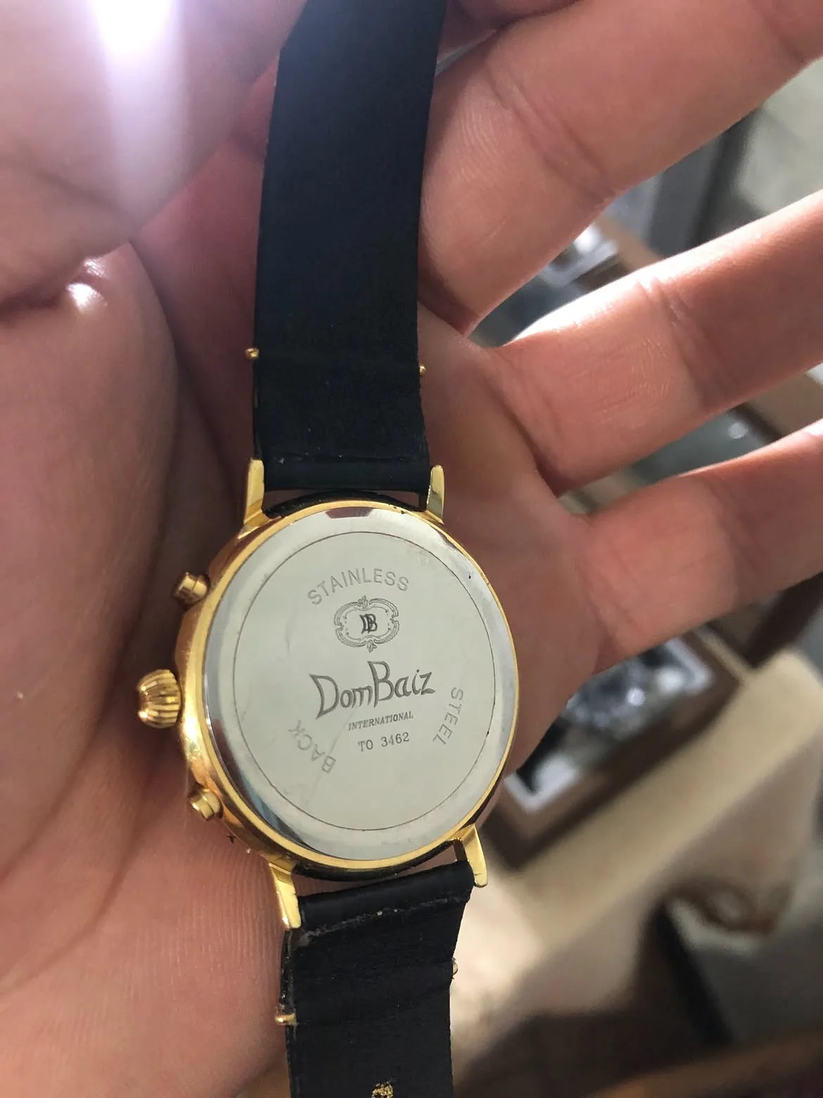 vintage Dom Baiz International Chronograph Watch featuring a classic white dial, three sub-dials, a date window at the 3 o'clock position, and a polished gold-plated case.