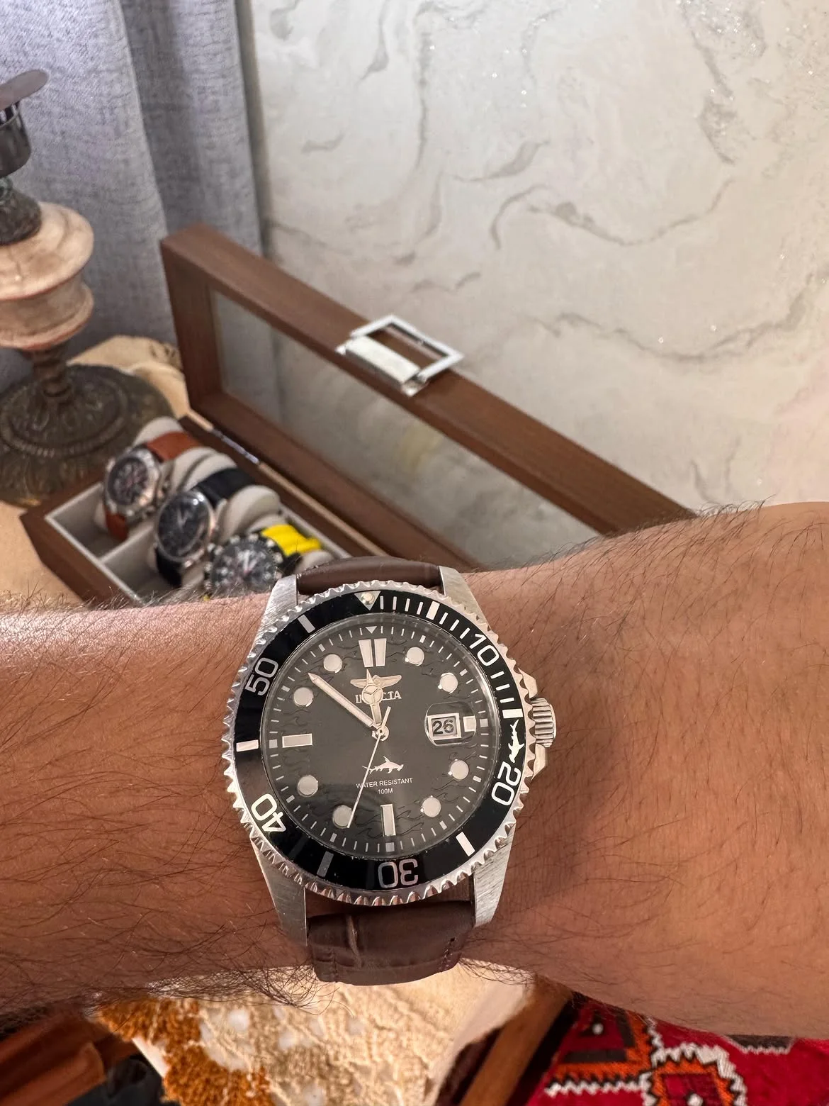 Cette montre au poignet est une Invicta Pro Diver (modèle similaire au 30018 ou 30806), dotée d'un boîtier en acier inoxydable, d'un cadran noir avec guichet de date et d'une lunette tournant