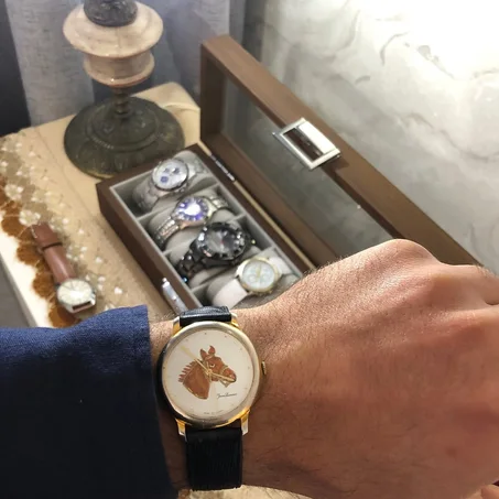 ⌚ Montre Pierre Lannier au boîtier doré se distingue par son cadran blanc illustré d'une tête de cheval caractéristique.