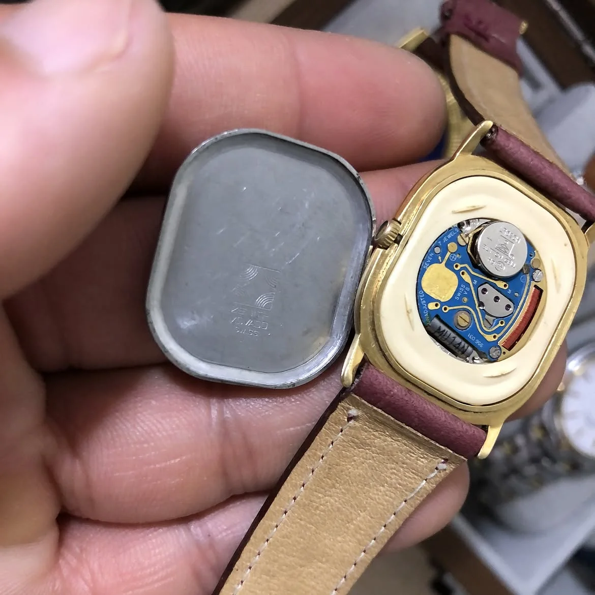 ⌚montre vintage Zenith quartz au boîtier ovale doré est dotée d'un élégant cadran bleu nuit et d'un bracelet en cuir grenu bordeaux.
