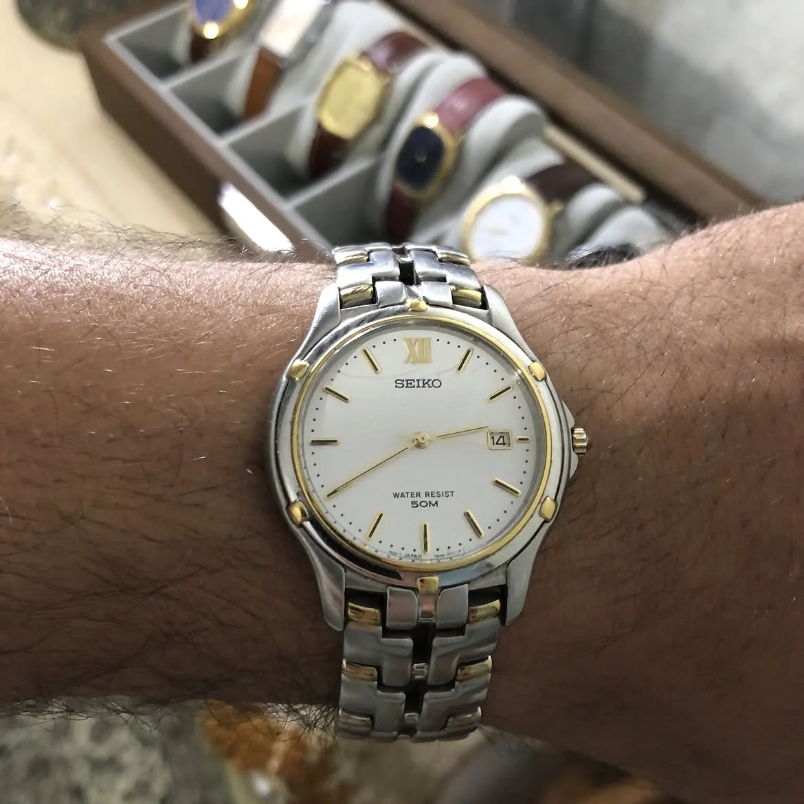 ⌚montre bicolore Seiko Quartz (référence 7N32-0049 ou similaire) se distingue par son cadran blanc épuré doté d'un guichet de date et d'une lunette ornée d'accents dorés.