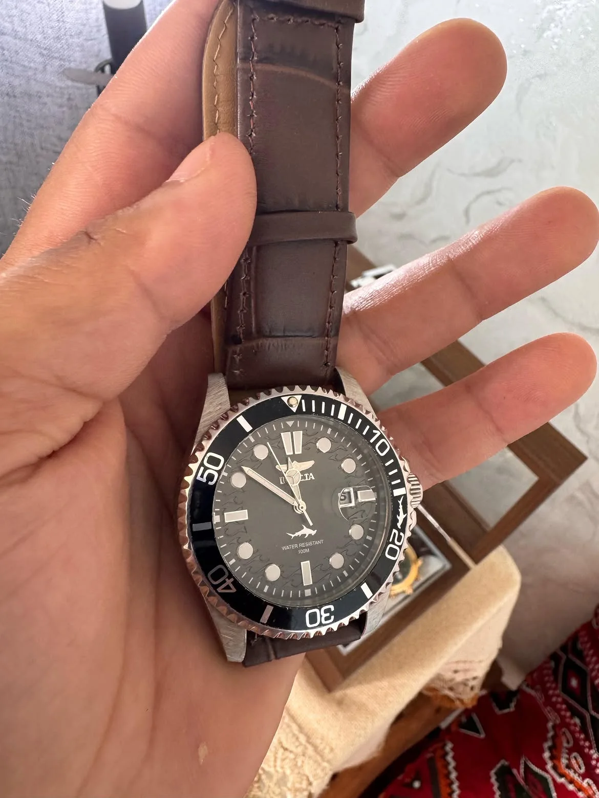 Cette montre au poignet est une Invicta Pro Diver (modèle similaire au 30018 ou 30806), dotée d'un boîtier en acier inoxydable, d'un cadran noir avec guichet de date et d'une lunette tournant