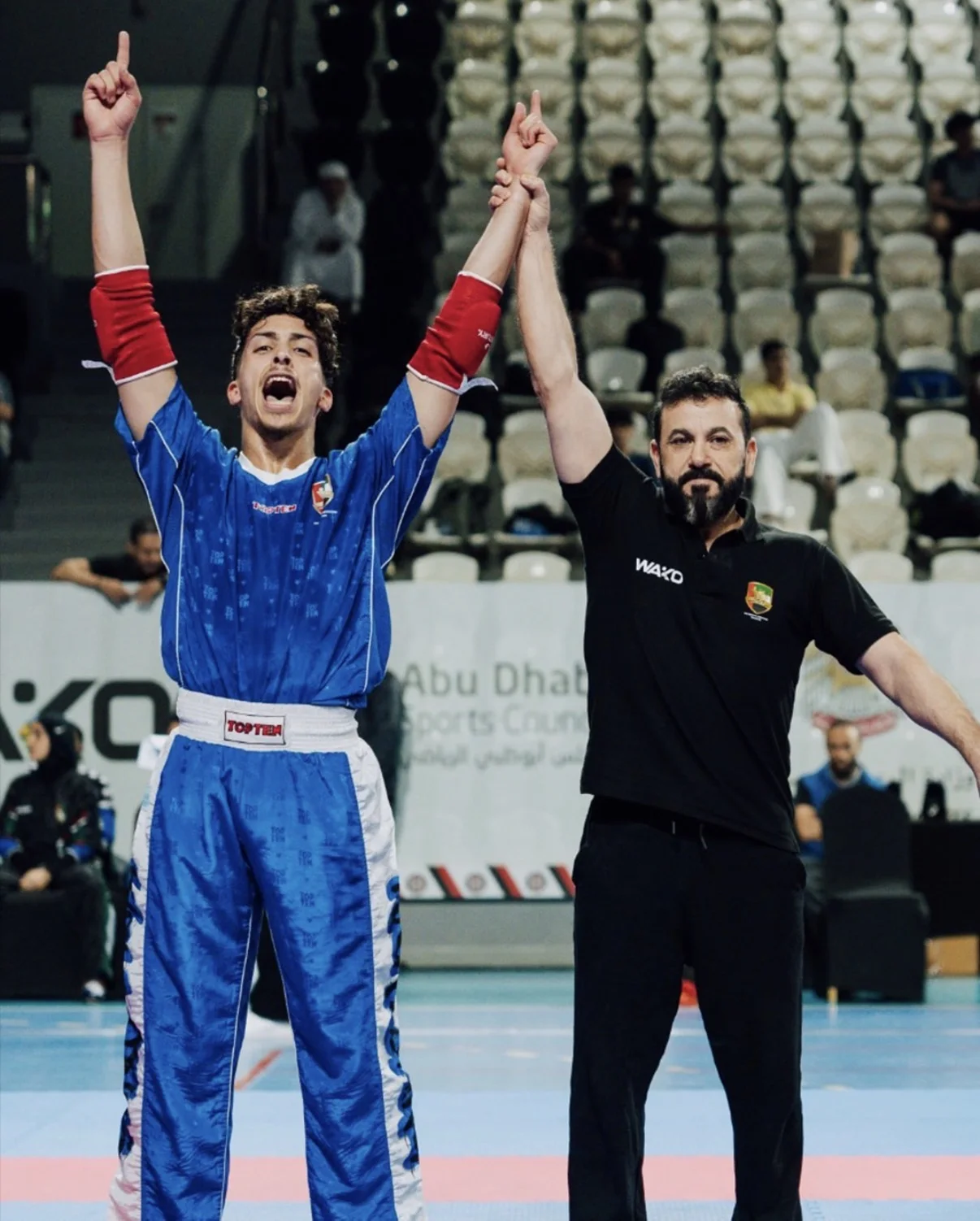 Coach Abdellah celebrating a kickboxing victory with the referee